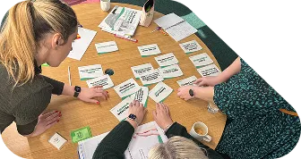 Participants sorting cards around a table during a Paseda coaching workshop